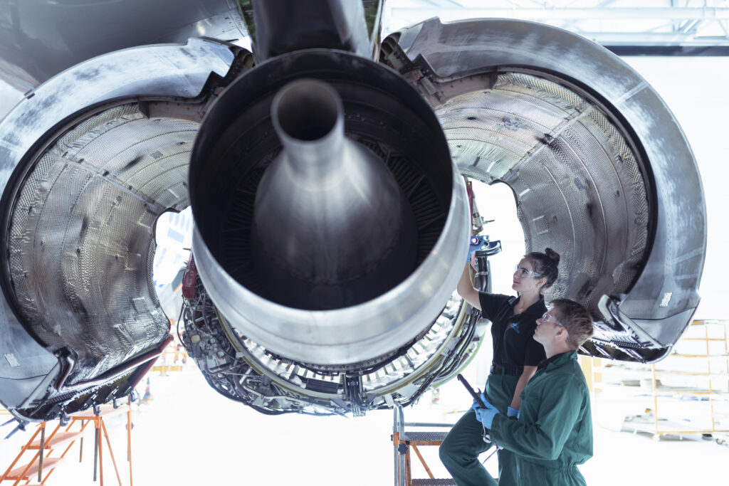 A female and male apprentice working on an engine